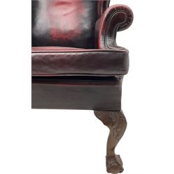 Georgian design hardwood-framed wingback armchair, upholstered in red leather, loose seat cushion and rolled arms, on acanthus carved ball and claw front feet 