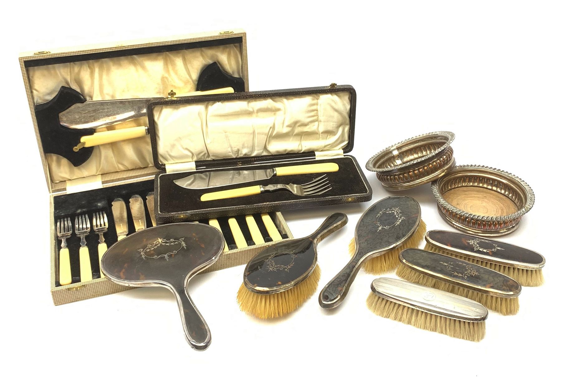 A silver mounted faux tortoiseshell dressing table set, comprising hand held mirror, two hair brushes, and two clothes brushes, each with inlaid swag to the back, hallmarked Lionel Smith & Co, Birmingham 1927, plus a silver mounted clothes brush with engine turned decoration and monogramed plaque, hallmarked William Neale & Son Ltd, Birmingham 1929, pair of silver plate on copper bottle coasters, cased set of fish servers, and cased set of fish eaters and servers, the knife blades marked Mappin & Webb. 