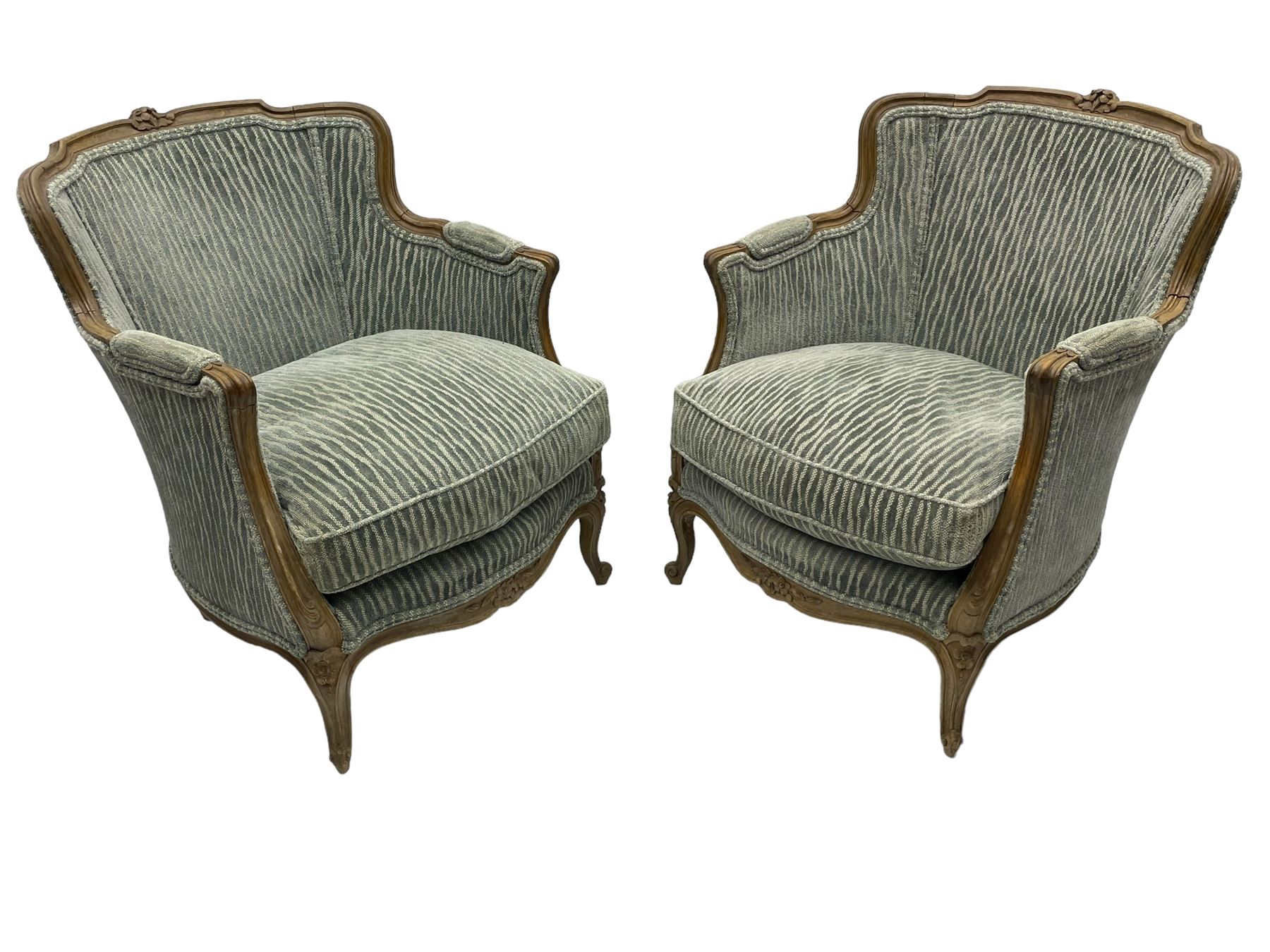 Colefax and Fowler - pair of French design beech framed armchairs, the moulded frame and cresting rail carved with flowers, scrolled arms and serpentine seats, cabriole supports with scroll carved terminals, upholstered in Colefax and Fowler fabric