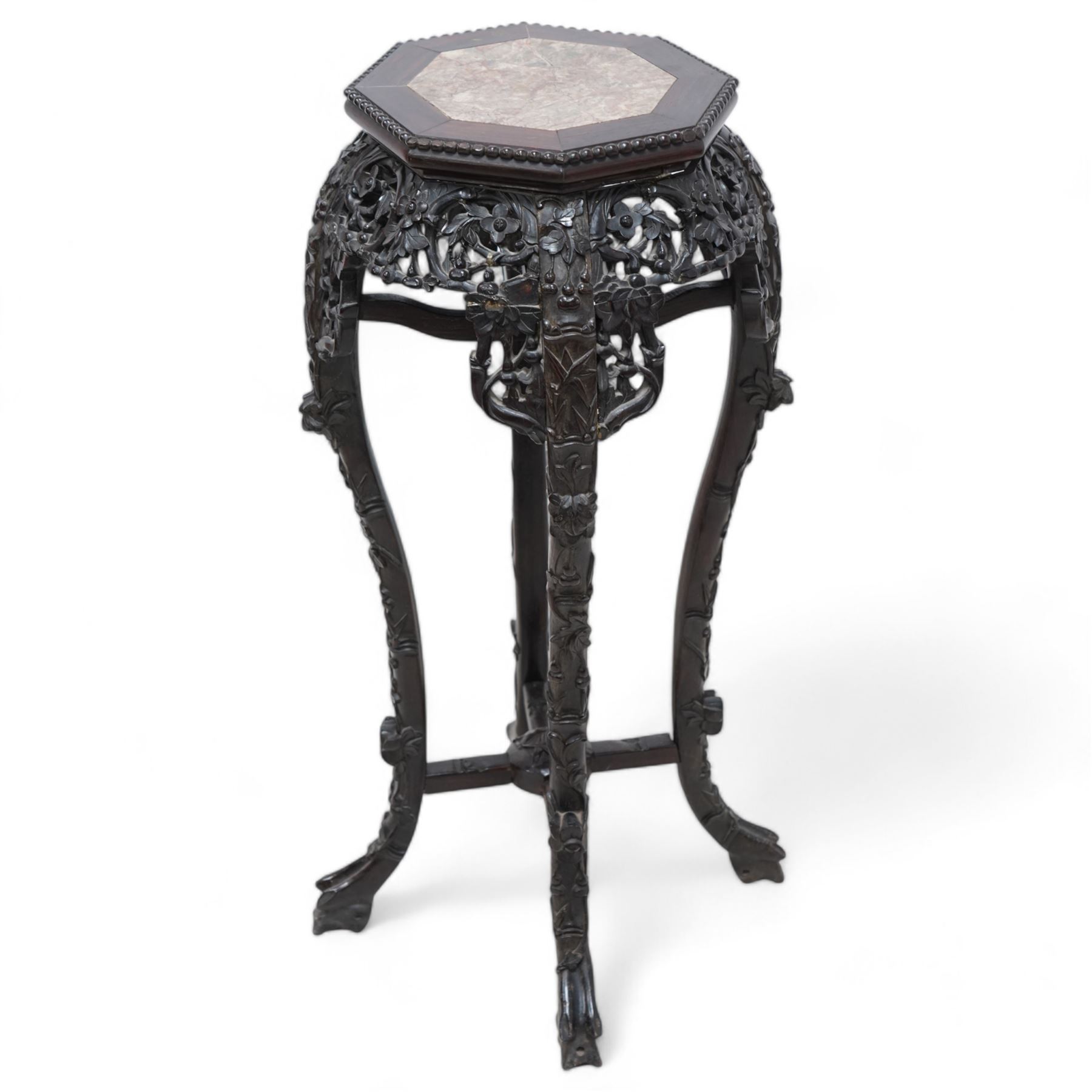 Early 20th century Chinese hardwood and marble top jardiniere or urn stand, octagonal top with central marble inset and bead edge, over pierced and carved foliate rails, the cabriole supports carved with trailing vines and protruding foliate decoration, united by X-stretcher on shaped claw feet