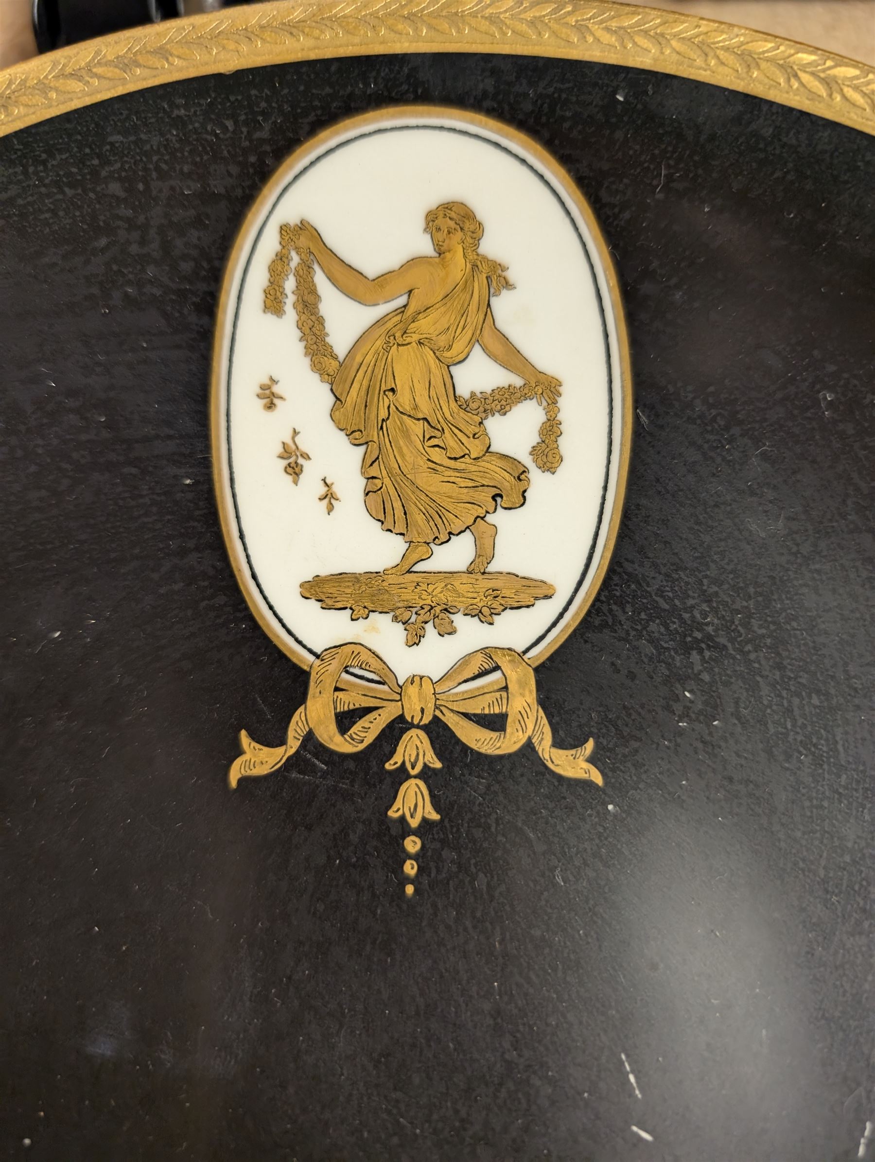 Pair of early 20th century Wedgwood tazzas, the black bowls with gilt foliate borders and painted in gilt with a classical female figure, with retailers mark for Phillip's Ltd Bond Street and printed maker's mark beneath, H6cm, D23.5cm