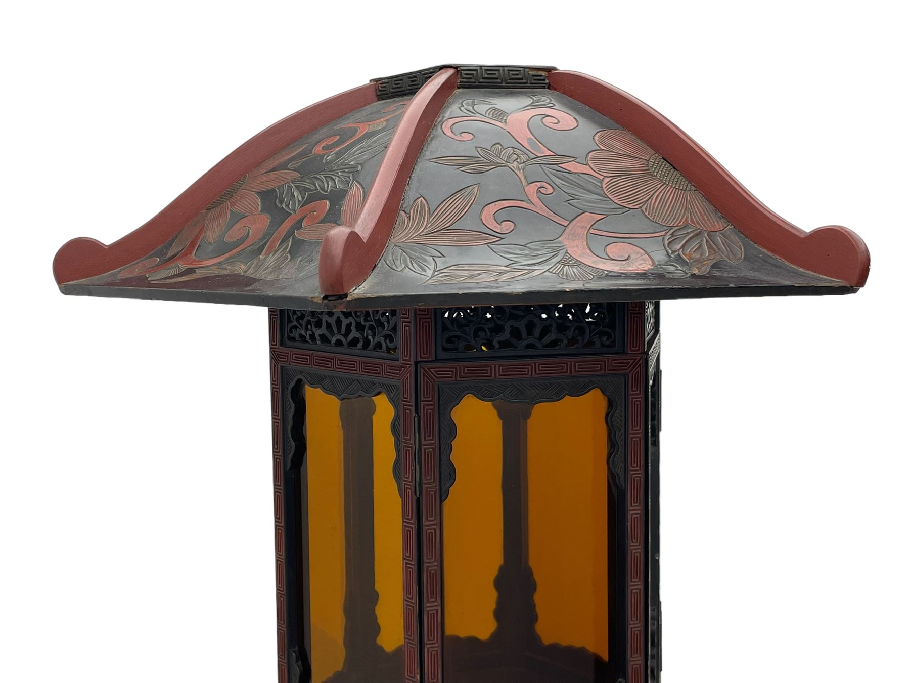 20th century Chinese black and red lacquered hardwood lantern stand, hexagonal shaped canopy top carved with flower heads and scrolls, the lantern fitted with amber tinted glass panes, pierced and carved upper panels, enclosed by two hinged doors, turned stem carved in relief with trailing vine leaves with fruits, stepped hexagonal base with carved decoration  