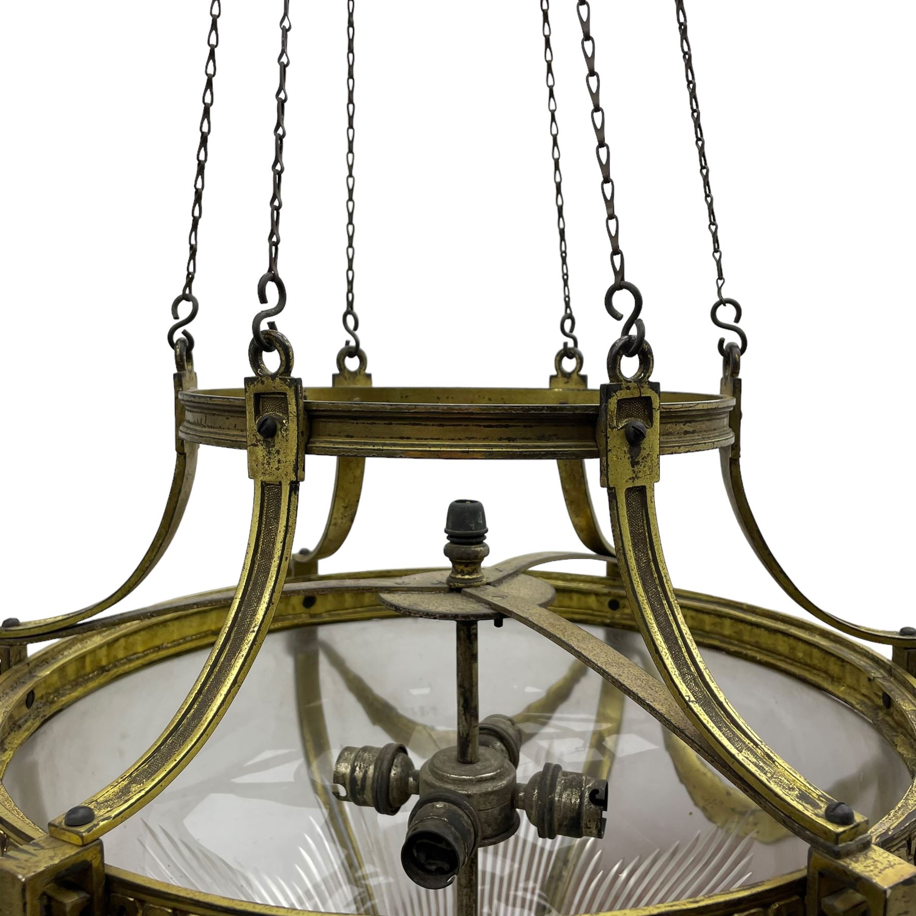 Edwardian brass ceiling light of circular bulbous form, moulded upper band over a guilloche cast central band united by shaped strapping, decorated with fruiting foliage festoons, fitted with frosted and vertical bevelled glass bowl, acanthus cast finial 