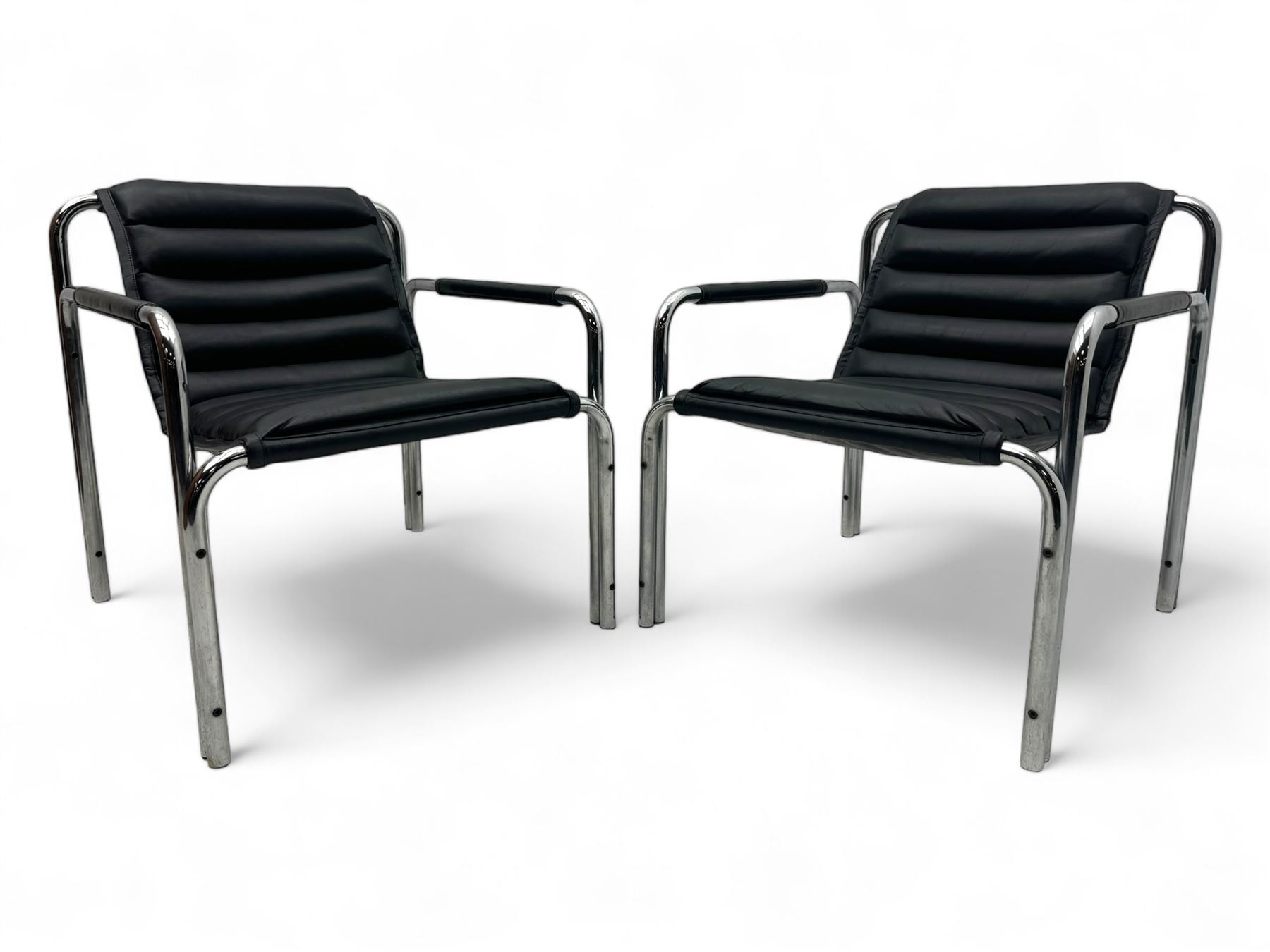 Baroumand Designs - pair of mid 20th century modernist armchairs, slung black leather seat with horizontal channel tufting, tubular chrome frame with curved arms, raised on tubular supports