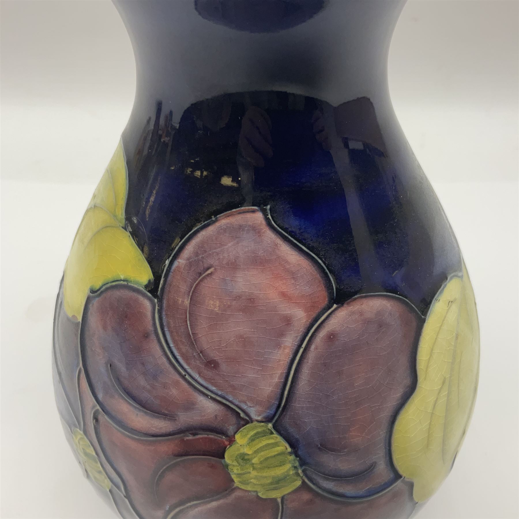 Moorcroft Clematis pattern vase of baluster form, upon a blue ground, with painted and impressed marks beneath, H22cm