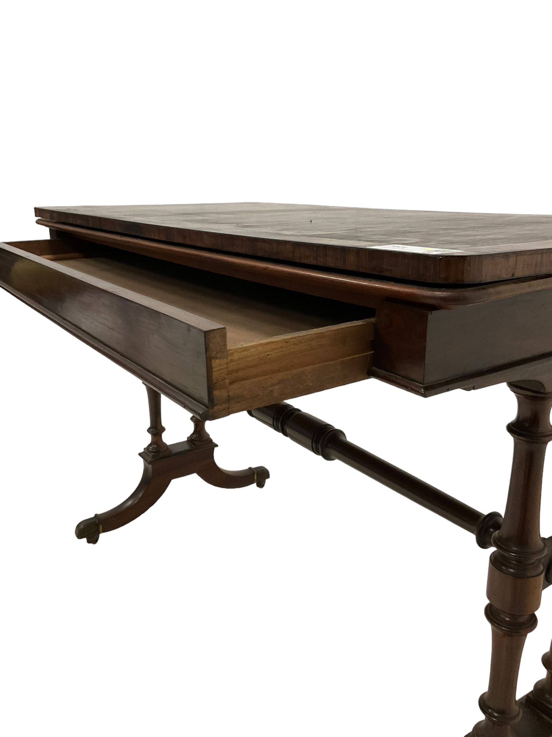 Regency rosewood card table, fold-over swivel action rectangular top with crossbanding, single frieze drawer, raised on turned end supports terminating in splayed feet with castors, joined by ring turned stretcher