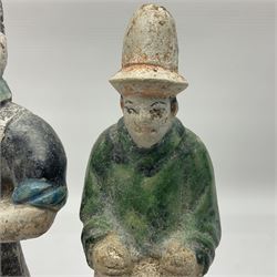 Three Chinese terracotta court attendant tomb figures, probably Ming Dynasty, two examples decorated in Sancai green glaze, the third example decorated in two tone blue glaze, each upon stepped square bases, tallest H22.7cm