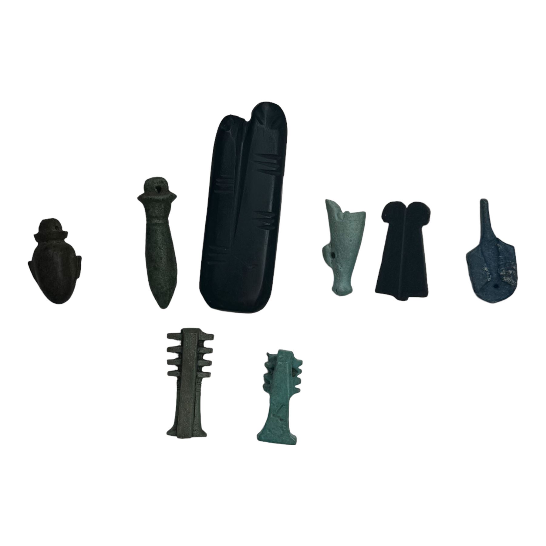 Eight Egyptian amulets, comprising black stone two figure amulet modelled as an outstretched index and middle finger, two faience Djed pillar amulets, obsidian double plume amulet, faience white crown amulet, papyrus amulet, heart amulet, and another blue example, largest two figure amulet L5.5cm