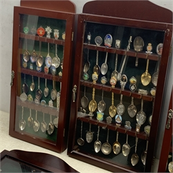 Five glazed wall display cases containing a selection of various souvenir spoons, comprising mostly silver plated examples. 