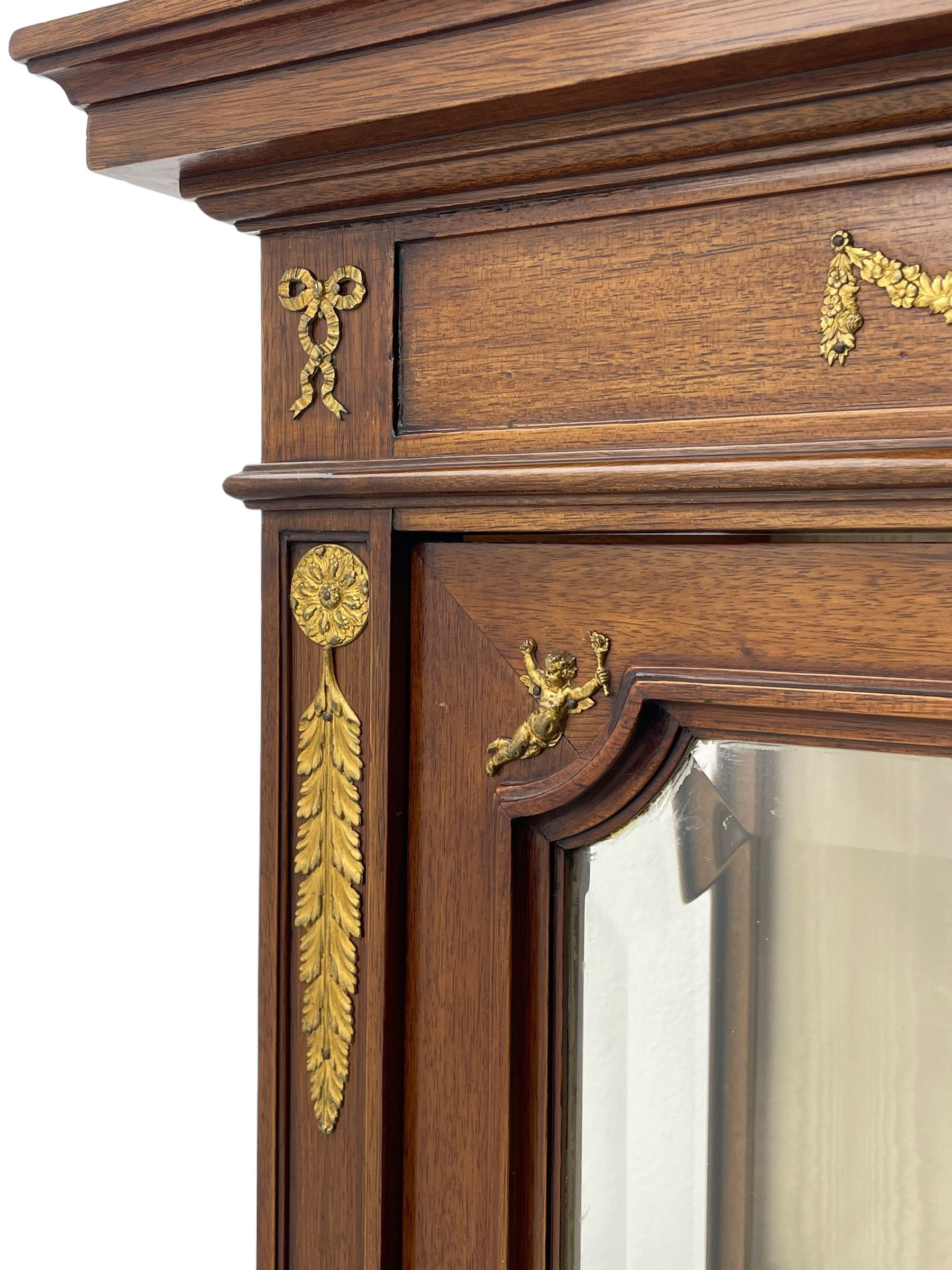 Early 20th century Louis XVI design mahogany vitrine display cabinet, projecting stepped cornice over recessed frieze decorated with gilt metal mounts of festoons and a bellflower wreath, fabric lined interior with two glass shelves, enclosed by bevel glazed door with lower panel, on two turned front feet 