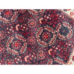 Persian Baluchi dark indigo and crimson ground rug, the field decorated with rows of repeating Pitrak motifs and surrounded by small bird and flower head motifs, floral urn decorated spandrels, repeating Pitrak border within guard stripes