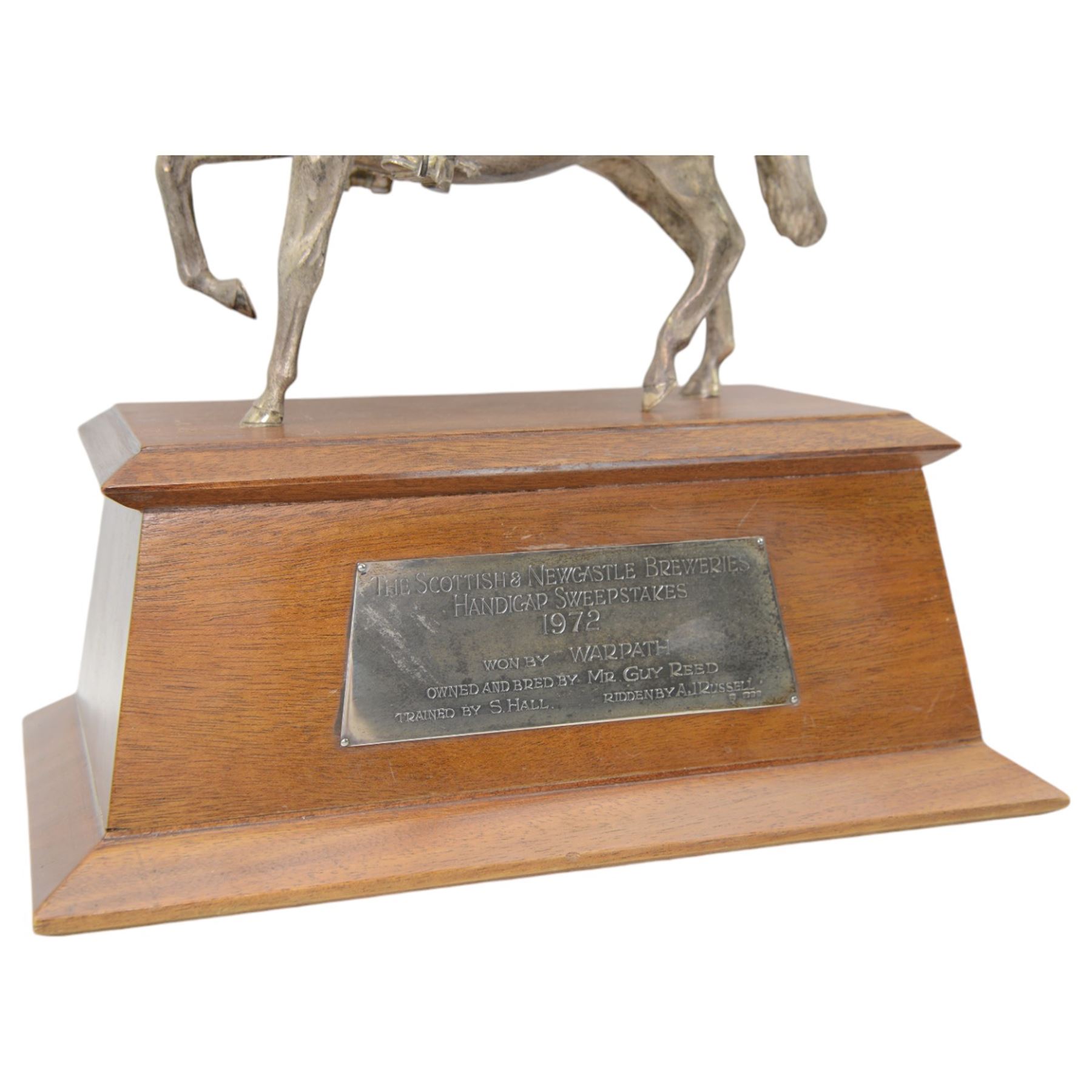 'The Scottish & Newcastle Breweries Handicap Sweepstakes 1972, Won by Warpath, Owned and Bred by Mr Guy Reed, Trained by S Hall, Ridden by A J Russell' - Cast silver figure of a cavalier on horseback 25cm x 21cm on a mahogany plinth with silver plaque 38cm x 33cm overall London 1969 Maker Edward Barnard & Son 