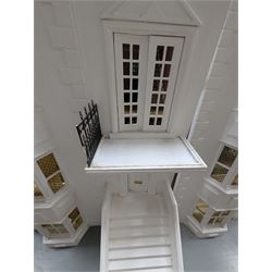 Large three storey modern dolls house, painted white with latticed windows, grey roof and metal fencing, with decorated interior, together with two dolls house garden rooms and two conservatories