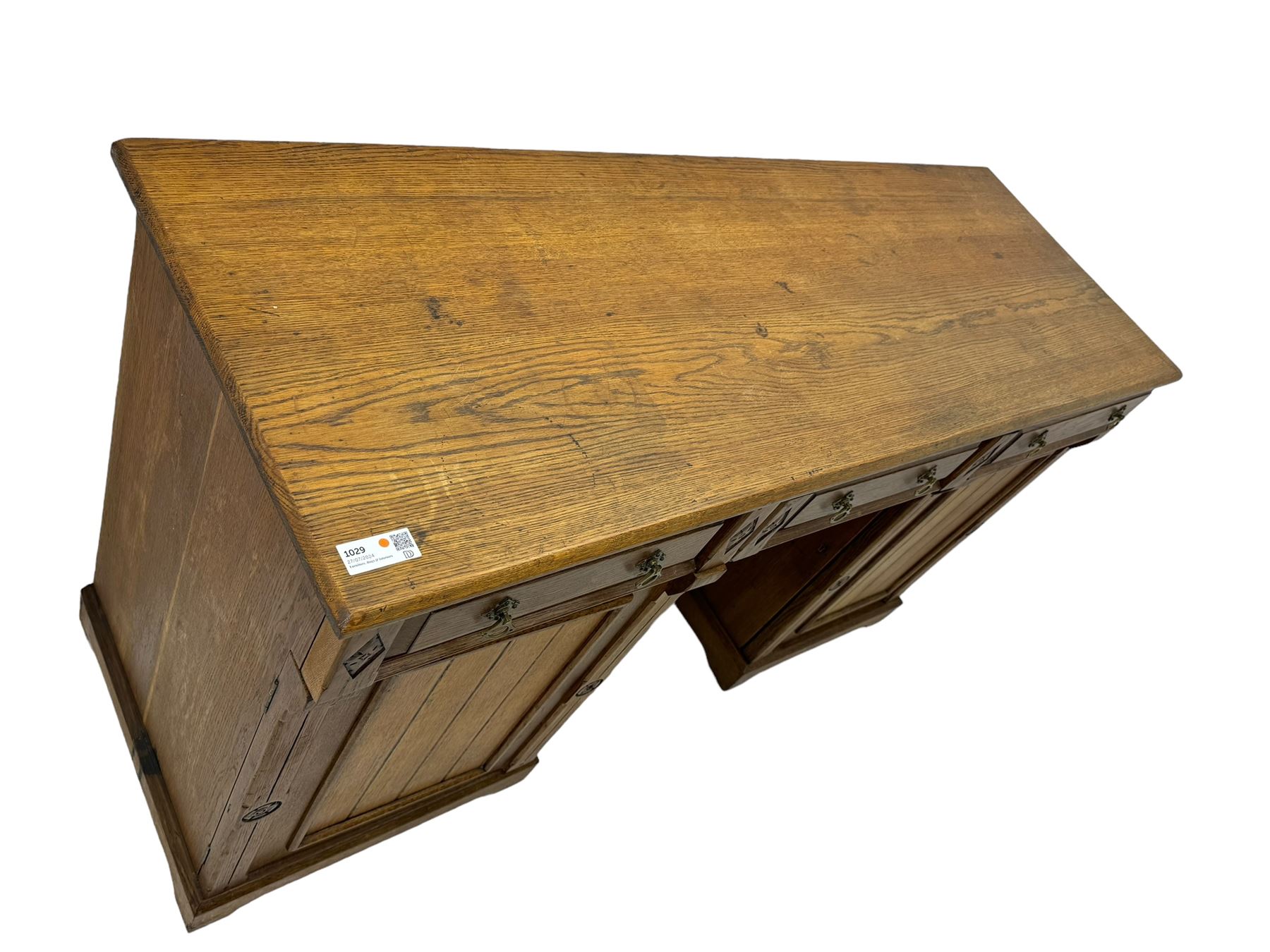 Late Victorian oak twin pedestal desk, chamfered rectangular top over three convex front edge drawers and two panelled cupboards, flanked by carved supports with roundels and diamond motif, on bracketed plinth base