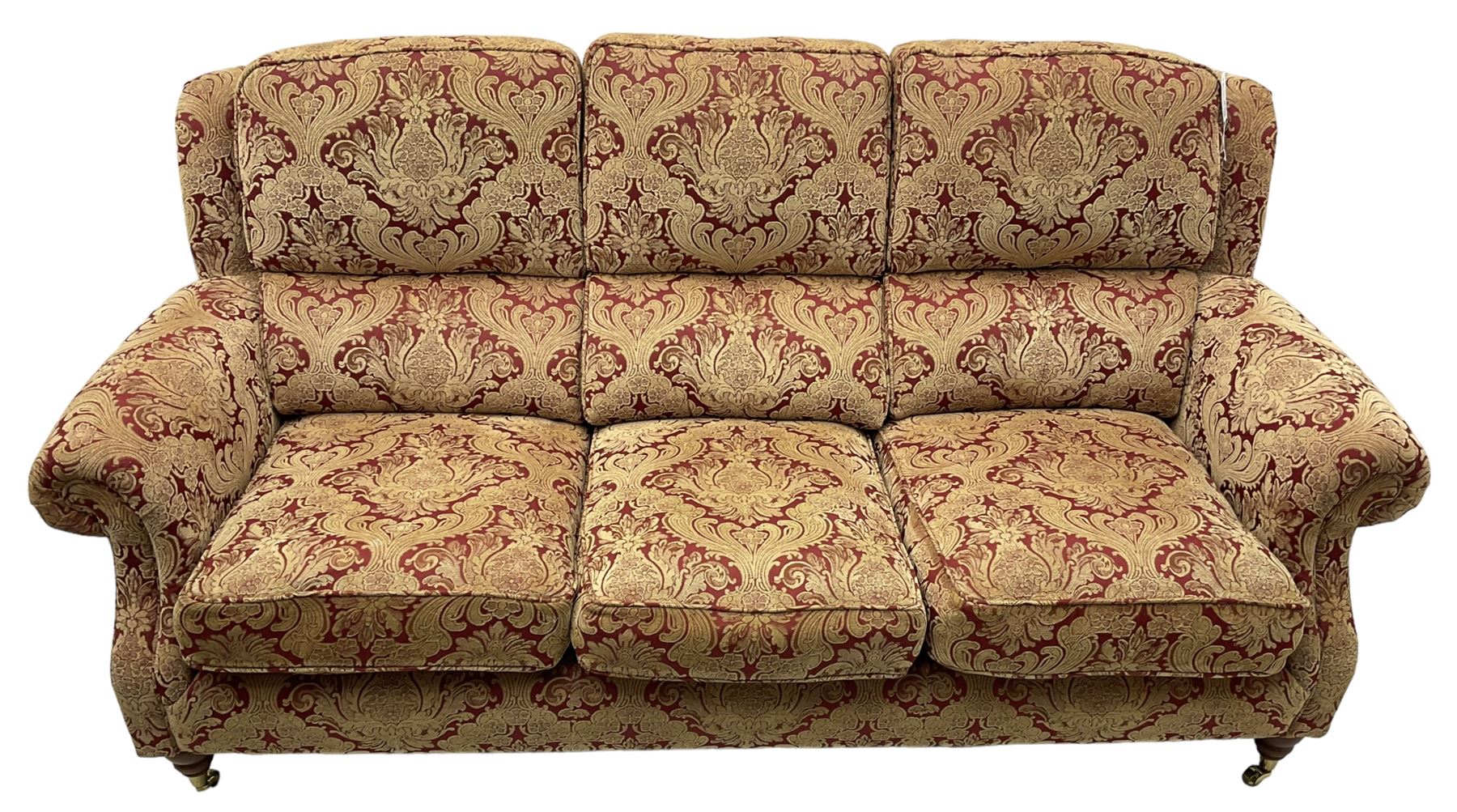 Parker Knoll - three-seat 'Oakham' hardwood-framed sofa, upholstered in red and gold floral pattern fabric, on turned feet with brass cups and castors 