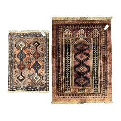 Persian prayer purple ground, decorated with three pointed buildings over tailing lozenge patterned field (111cm x 82cm); and a small Persian rug or mat, overall geometric design (81cm x 56cm)