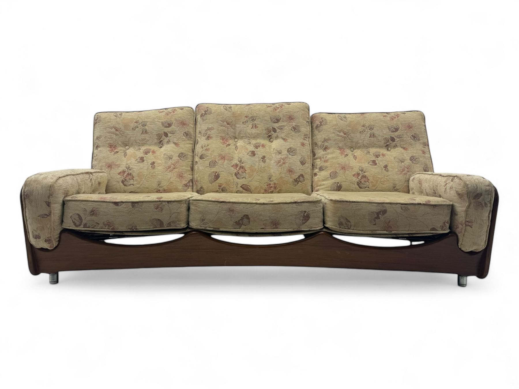 Mid-20th century three-seat sofa with floral patterned upholstery, supported by a sculpted teakwood frame with curved cutout detailing, loose cushioned back and seat, on tubular metal feet