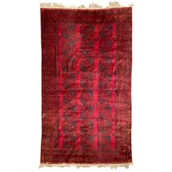 Afghan red ground Bokhara carpet, three rows of large Gul motifs, within multi-band border...