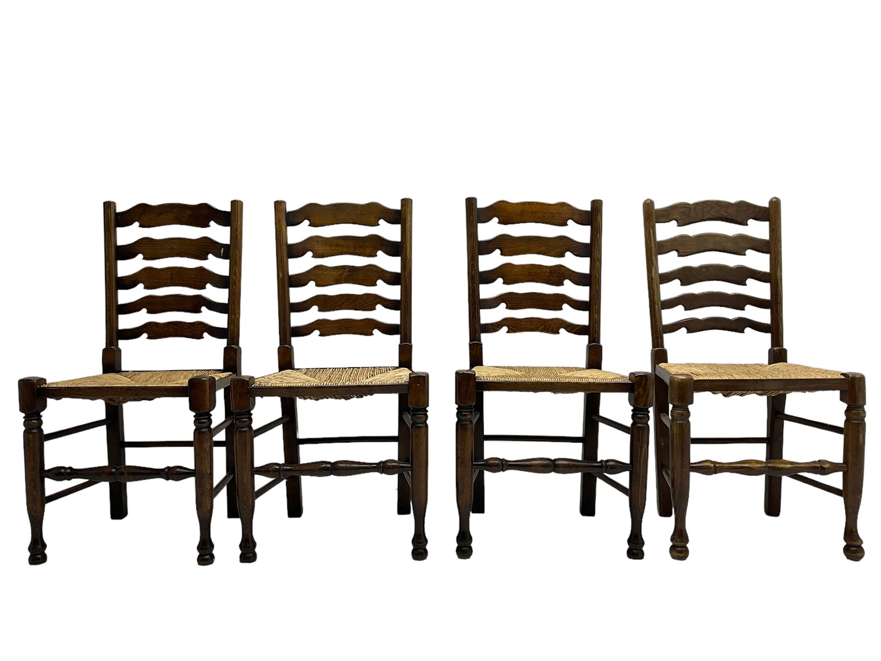 Matched set of eight (7+1) oak ladder back dining chairs, waved ladder back over rush seats, on turned supports joined by turned stretchers