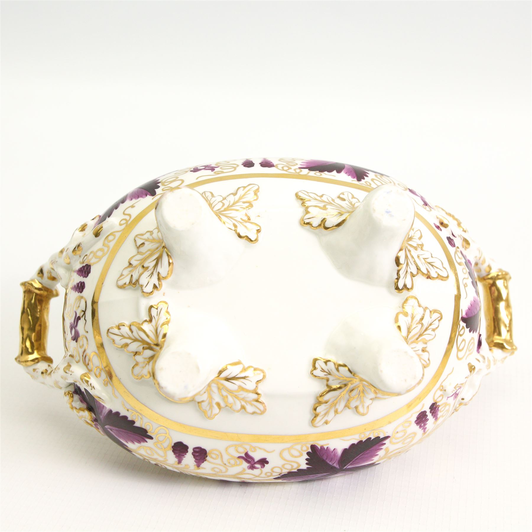 Pair of early 19th century porcelain sauce tureens and covers on stands, possibly Coalport, painted with bands of purple and gilt fruiting vines, within gadroon borders, the stands with naturalistic oak leaf and entwined moulded  handles, the covers with flower knop handles, stand L24cm, overall H18cm