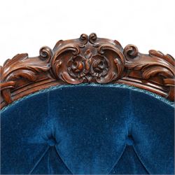 Victorian walnut framed open armchair, curled leaf carved cresting rail over scrolled and shaped arms, upholstered in buttoned blue velvet fabric, on cabriole feet