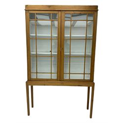 Georgian stripped pine bookcase display cabinet, plain moulded cornice over two glass-panel doors with multiple panes, enclosing white painted interior with three shelves, raised on square supports