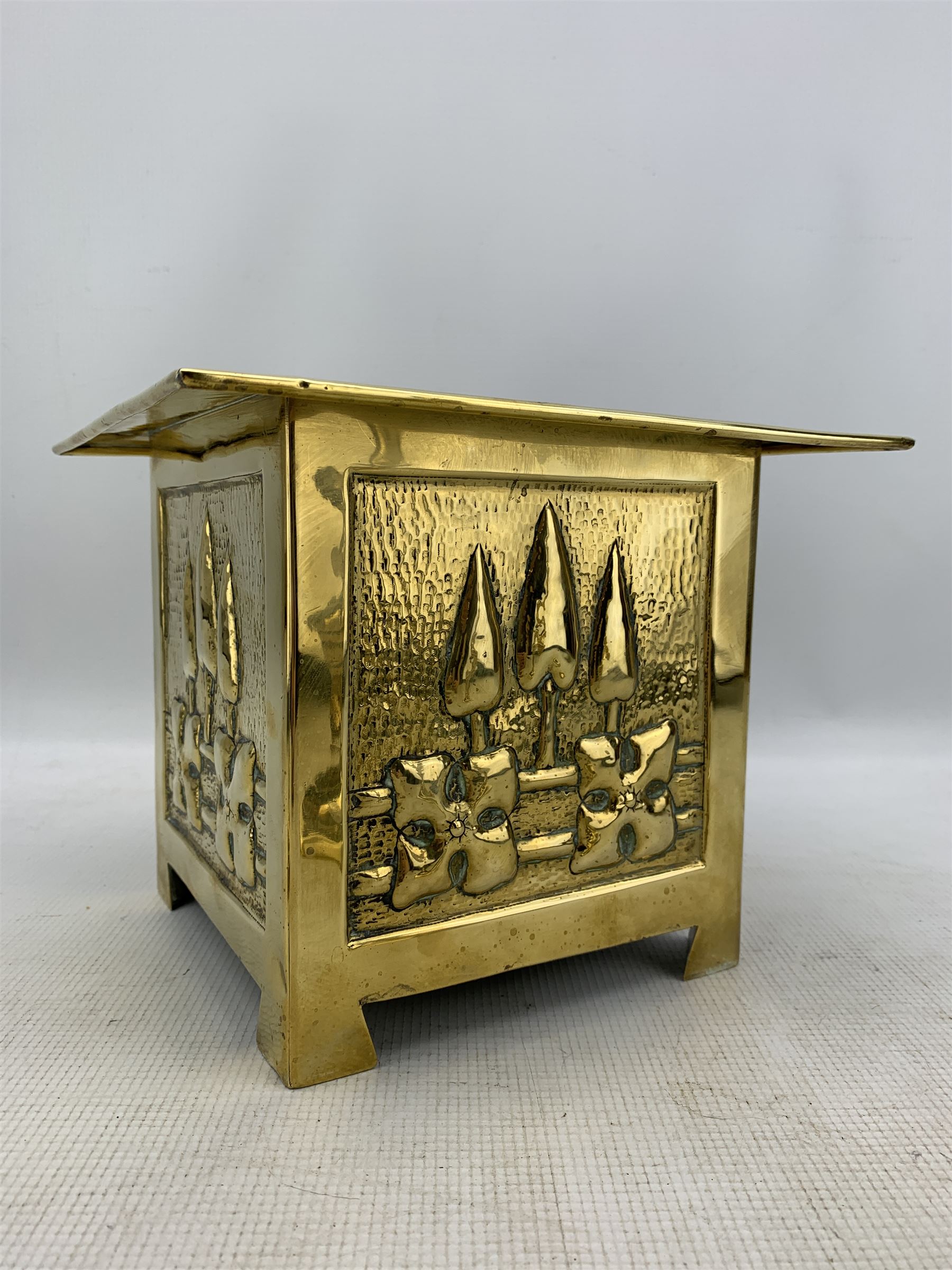 Arts and Crafts square brass planter, probably Glasgow School, with a raised pattern of stylised trees and foliage 23cm x 19cm and pair of brass candlesticks H25cm (3)