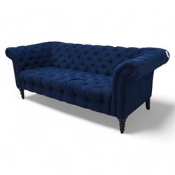 Chesterfield three-seat sofa, traditional shape with rolled arms, upholstered in deep blue buttoned fabric, on black finish turned front feet 