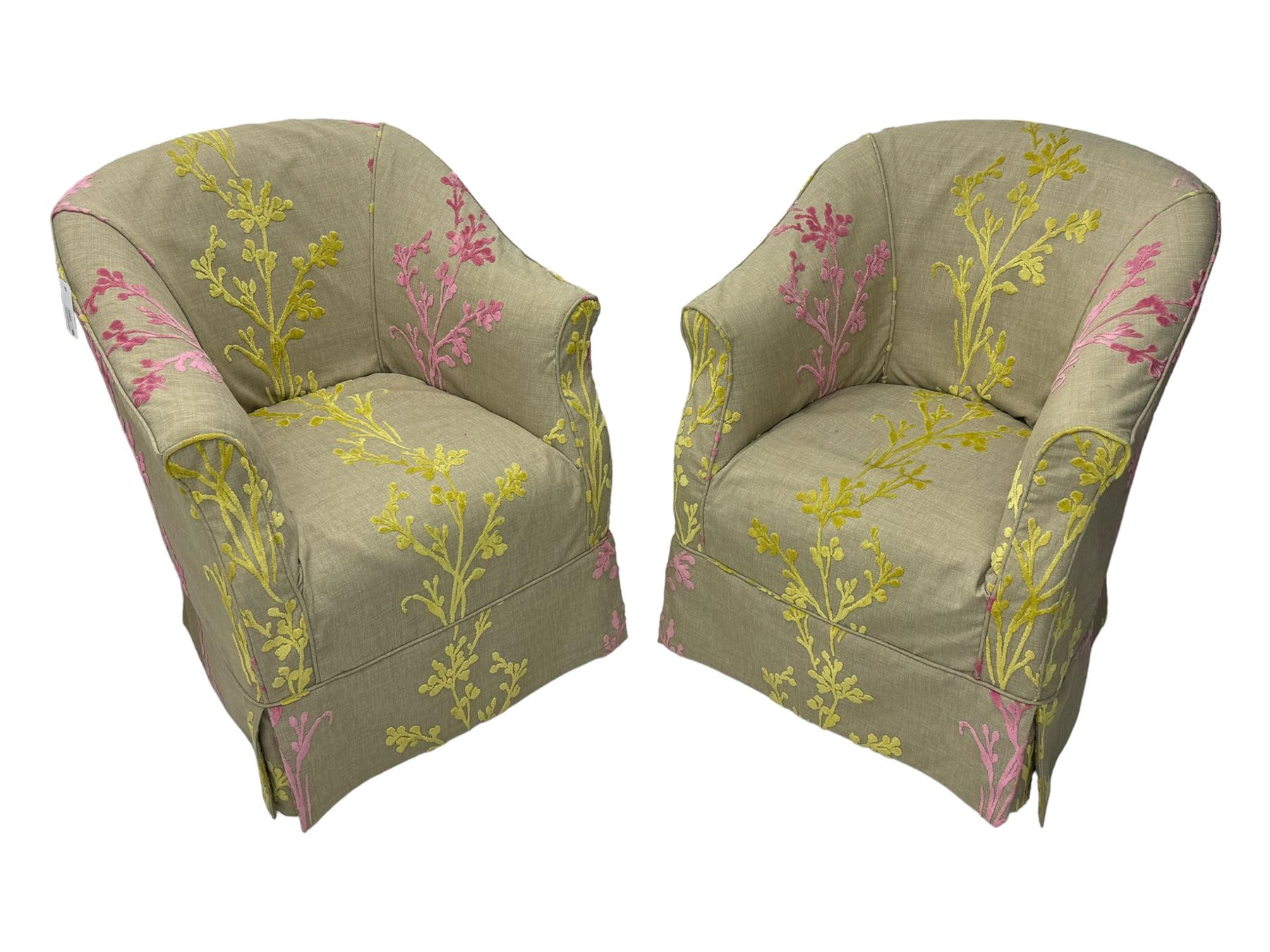 Pair of tub-shaped armchairs, mahogany frame loosely covered by branching floral pattern cover in pink and  yellow hues, skirted base, on concealed splayed rear and tapered front supports