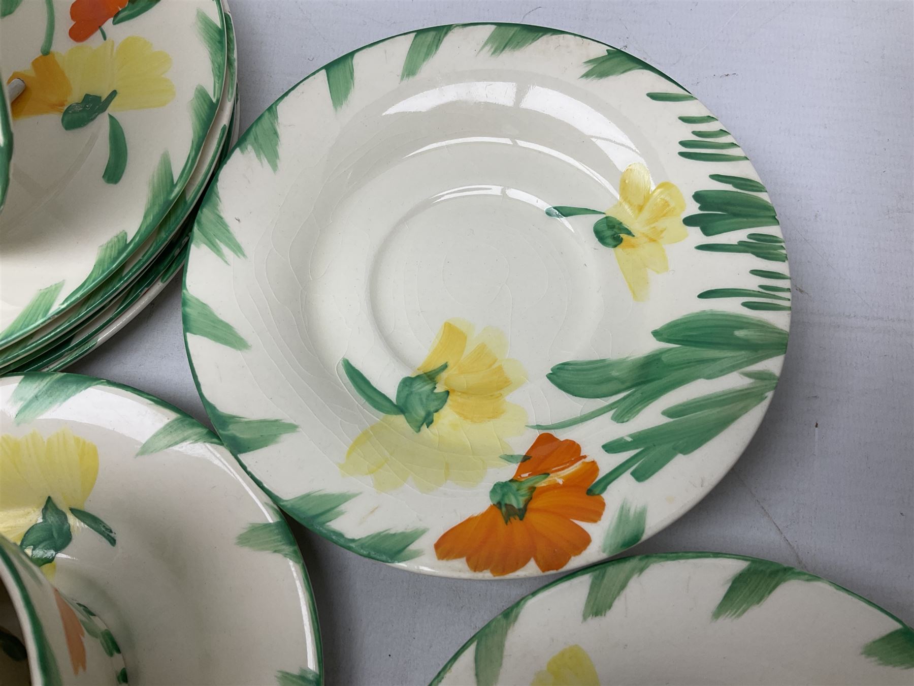 Art Deco tea service for six by Myott, Son & Co, painted with stylised orange and yellow flowers amongst green foliage on plain ground, together with a similar unmarked part tea service decorated with blue flowers