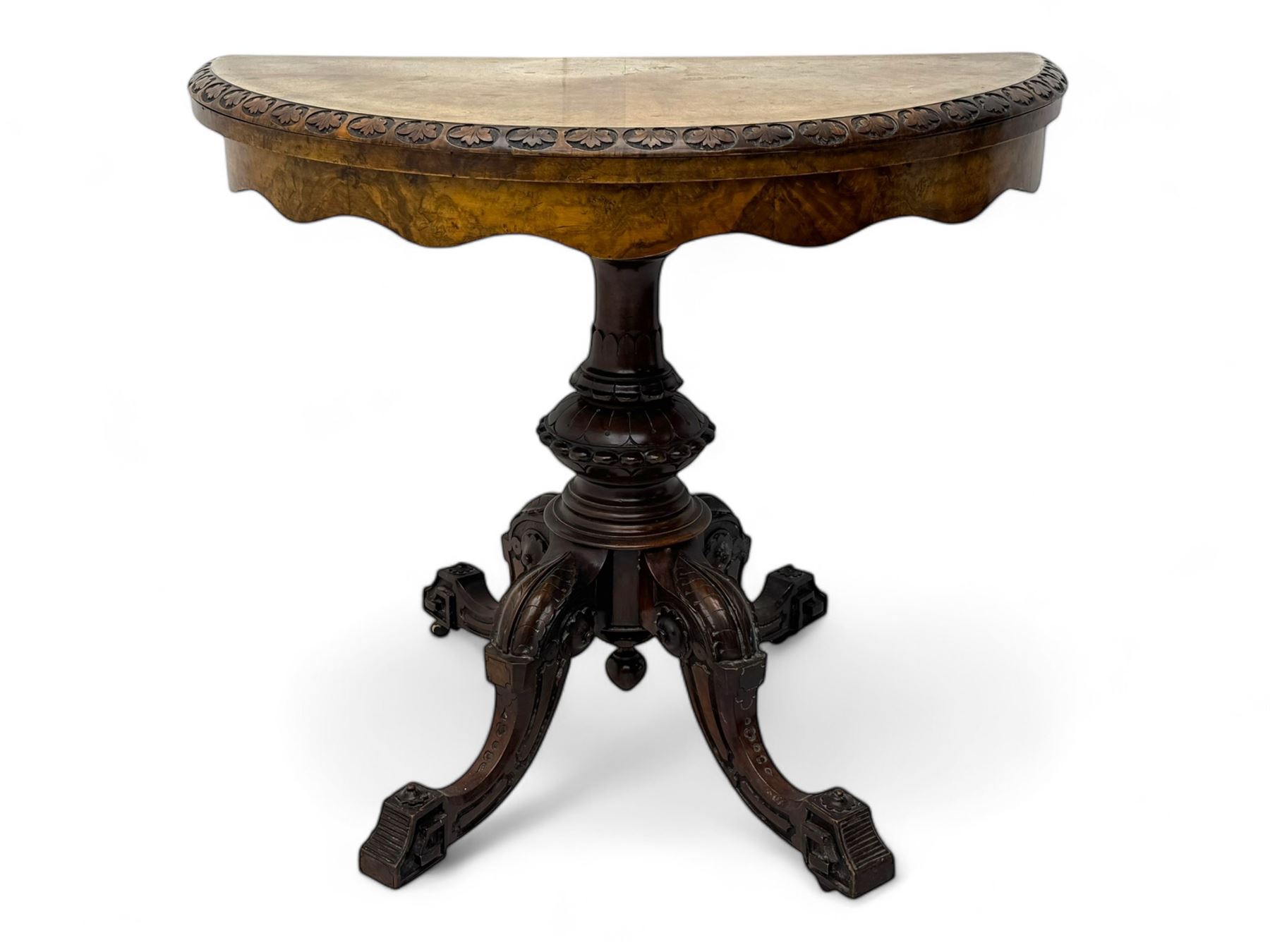 Victorian walnut demi-lune card table, circular fold-over top with foliate carved edge, revealing green baize-lined playing surface over scalloped apron, raised on a turned and carved pedestal with four splayed scroll supports with castors