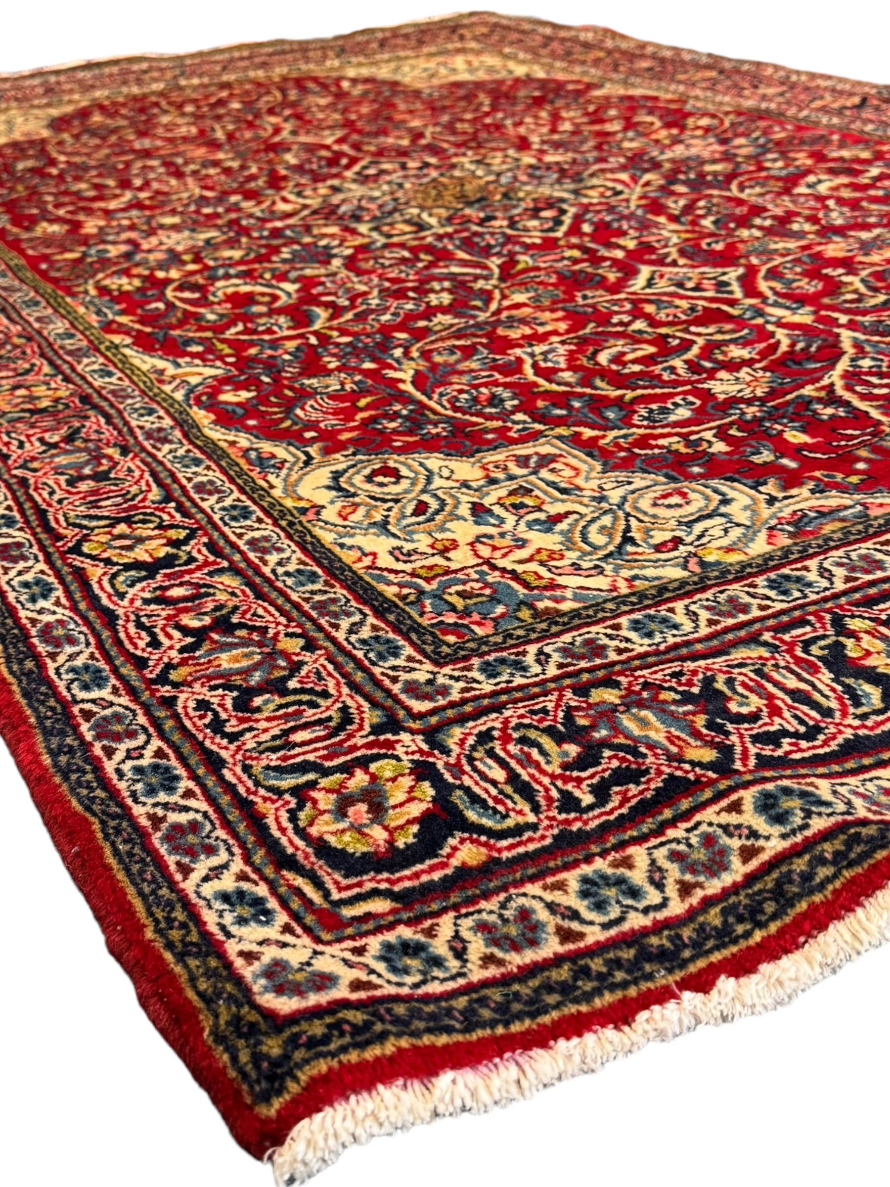 North west Persian Sarouk crimson ground rug, central floral medallion surrounded by scrolling branches decorated with foliage and stylised plant motifs, the main border decorated with repeating scrolling design with floral motifs, within guard stripes 