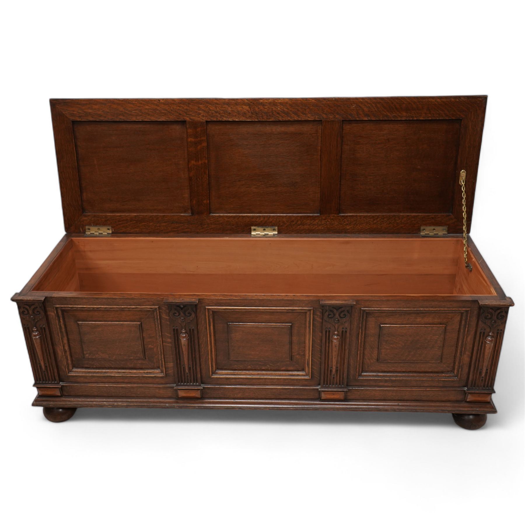 Early 20th century oak window box-seat, rectangular hinged top upholstered in blue fabric, fielded panelled front decorated with fluted and moulded uprights, raised on compressed bun feet