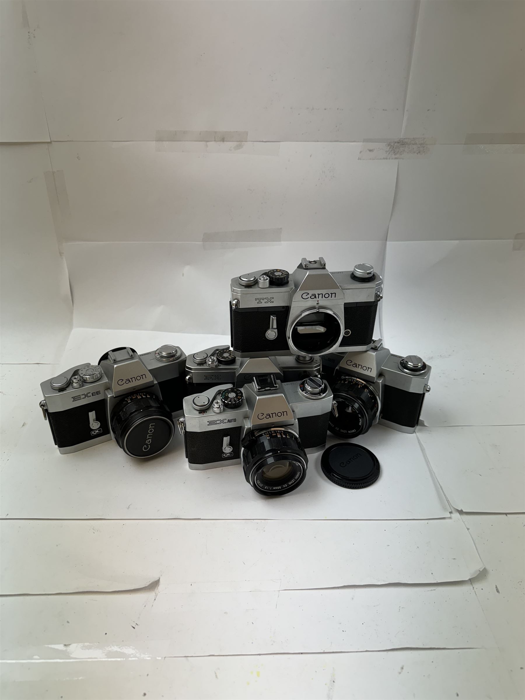 Five Canon SLR camera bodies all in silver and black finish, to include TX serial no. 144016, FX serial no. 210103, EX EE serial no. 136634 and two EX Autos, serial nos. 134020 & 157688, three with Canon 50mm 1:18 lenses