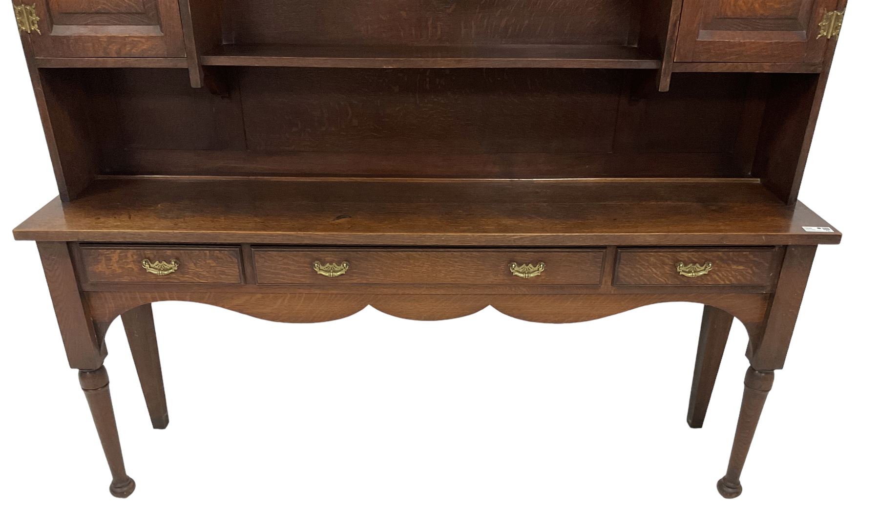 Early 20th century Georgian design oak dresser, projecting cornice with shaped apron over a three-tier plate rack with flanking fielded spice cupboards, the base fitted with three drawers, on turned supports