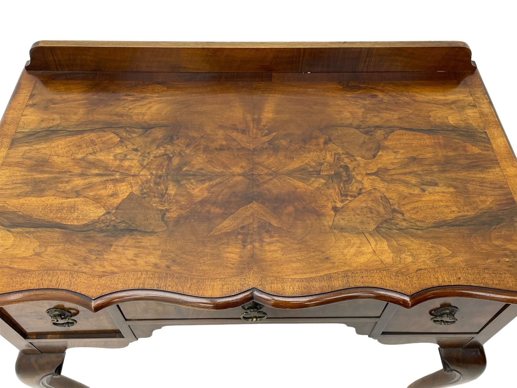 Mid-to-late 20th century figured walnut side table, raised back over figured top with cross banding and shaped front, fitted with three drawers, on cabriole supports with carved terminals 