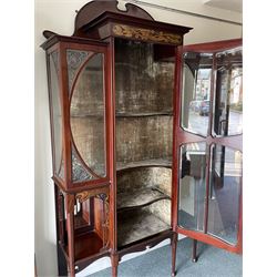 Art Nouveau period inlaid mahogany display cabinet, raised shaped and moulded pediment over projecting moulded cornices, the upper frieze inlaid with trailing branches and tulips, single astragal and bevel glazed door enclosed velvet lined interior fitted with shelves, flanked by curved glass panes decorated with pierced metal foliate spandrels, lower flanking shelves with mirror backs enclosed within shaped and pierced rails inlaid with flower heads, on tapering octagonal supports terminating to compressed pad feet, the lock stamped 'Salmon Bros, London' 