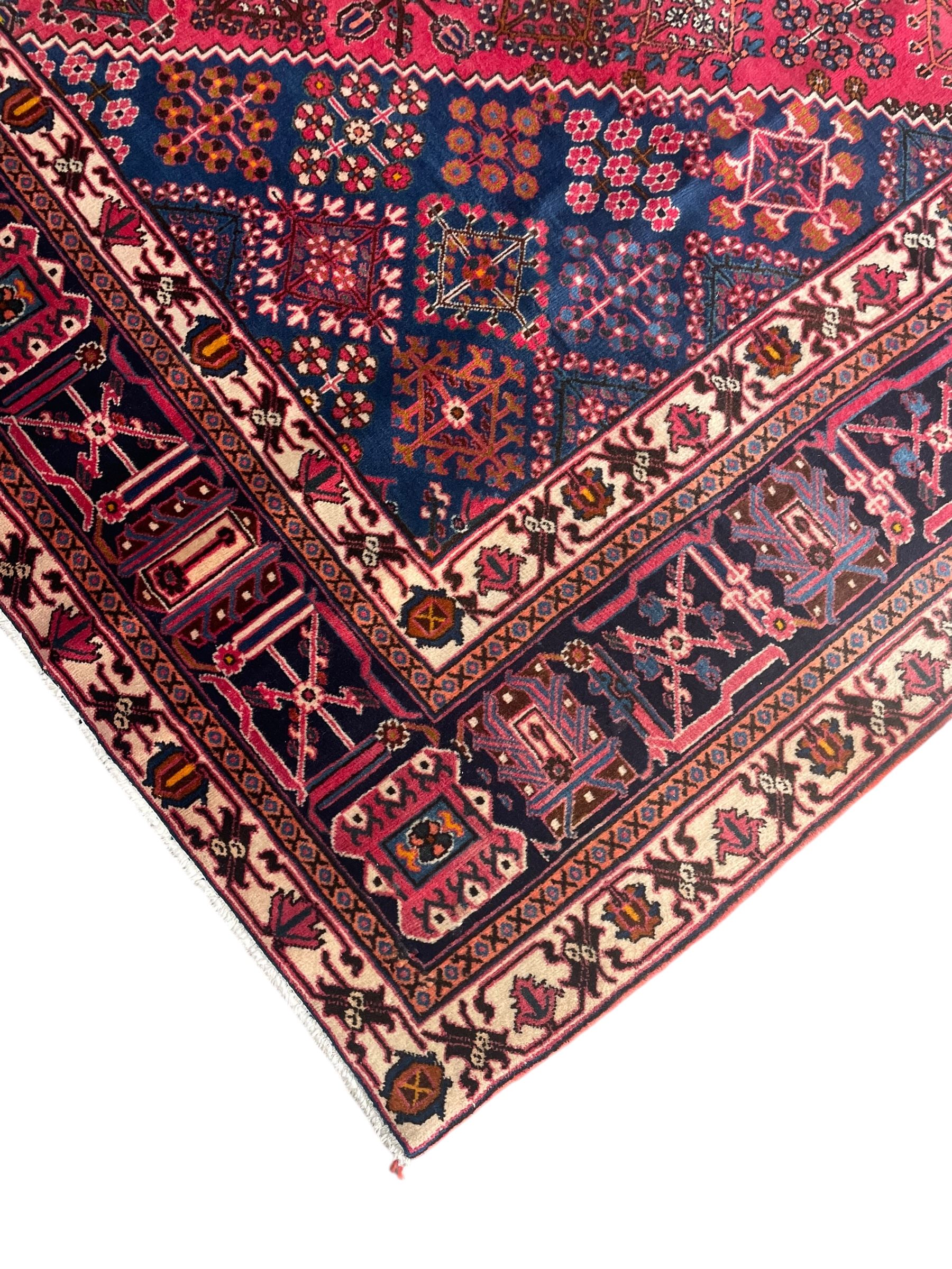 Persian Joshaghan red ground rug, the medallion, field and spandrels decorated with Pitrak and tree of life motifs, the border with repeating design decorated with stylised plant motifs, within guard stripes