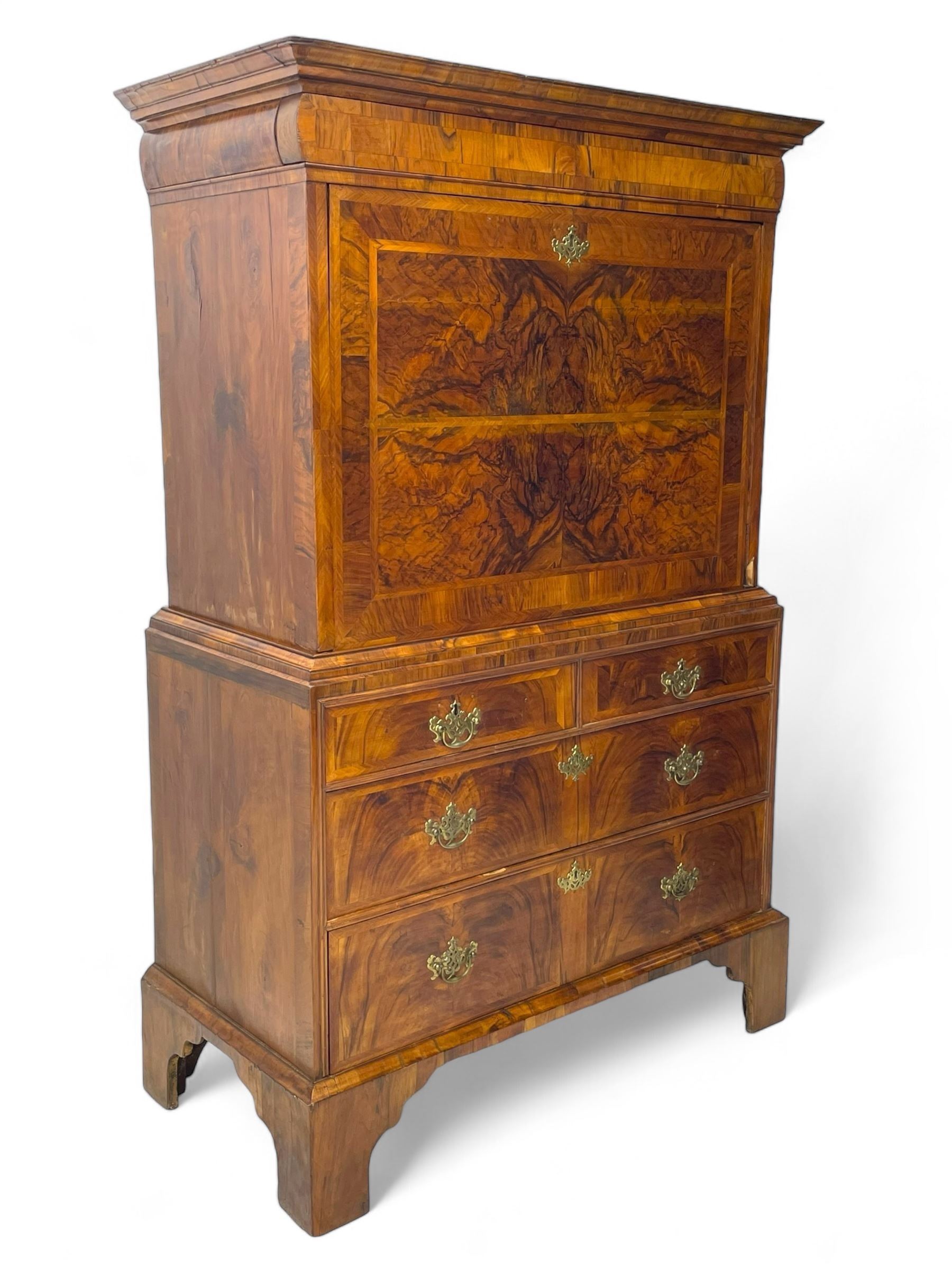 Early 18th century William & Mary figured walnut escritoire, projecting moulded cornice over shallow frieze drawer, the figured fall front enclosing interior fitted with small drawers, cupboards, pigeon holes and hidden drawers, the lower section fitted with two short and two long graduating drawers, on tall bracket feet 