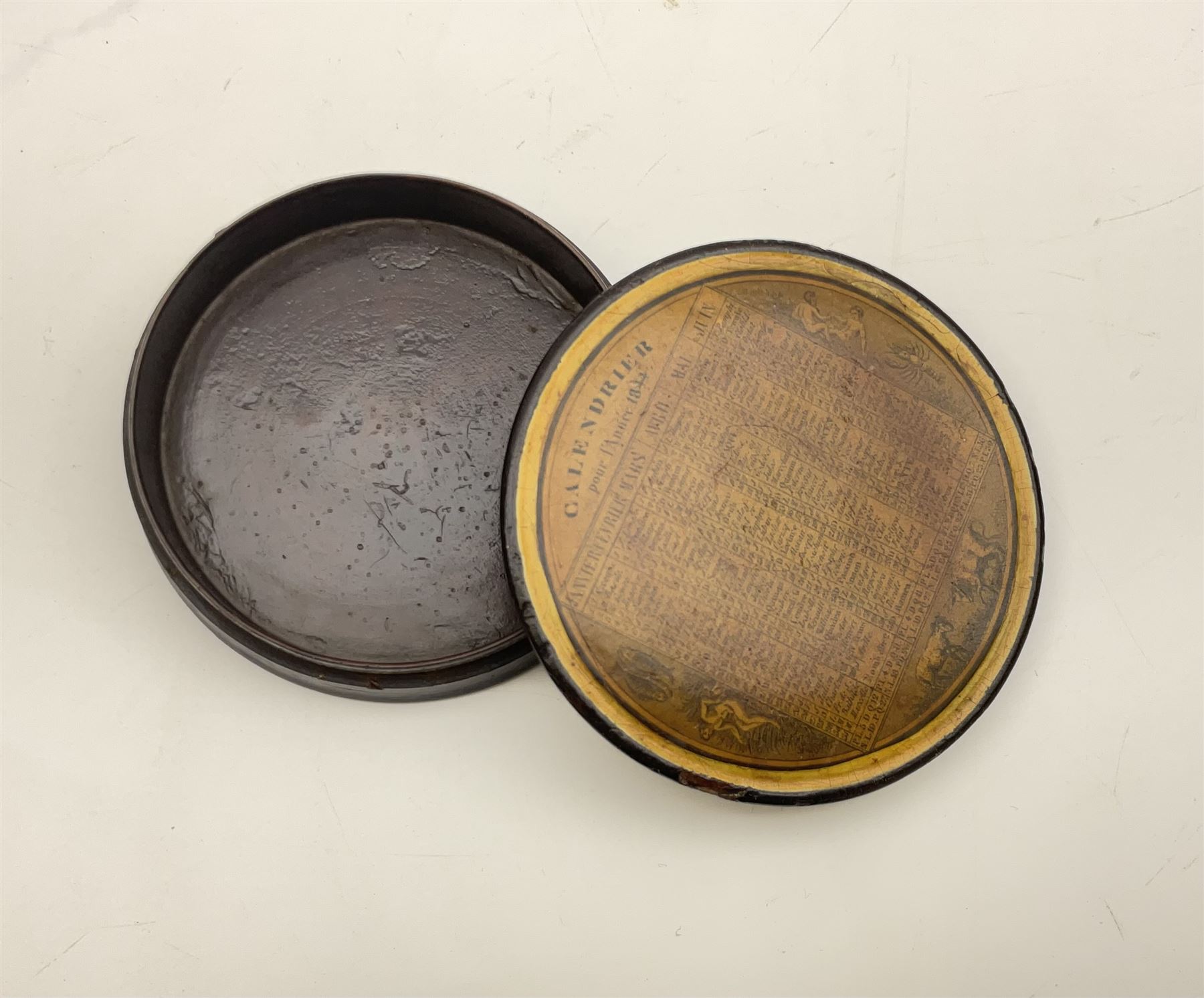 Two 19th century French papier-mâché snuff boxes, each of circular form decorated with the French calendar and detailed 'Calendrier pour l'an 1839' and 'Calendrier pour l'annee 1844' to top and ''Saisons' to base, further detailed with the months, days and additional notations alongside symbols from the zodiac, larger example D9.5cm, smaller example D8.5cm