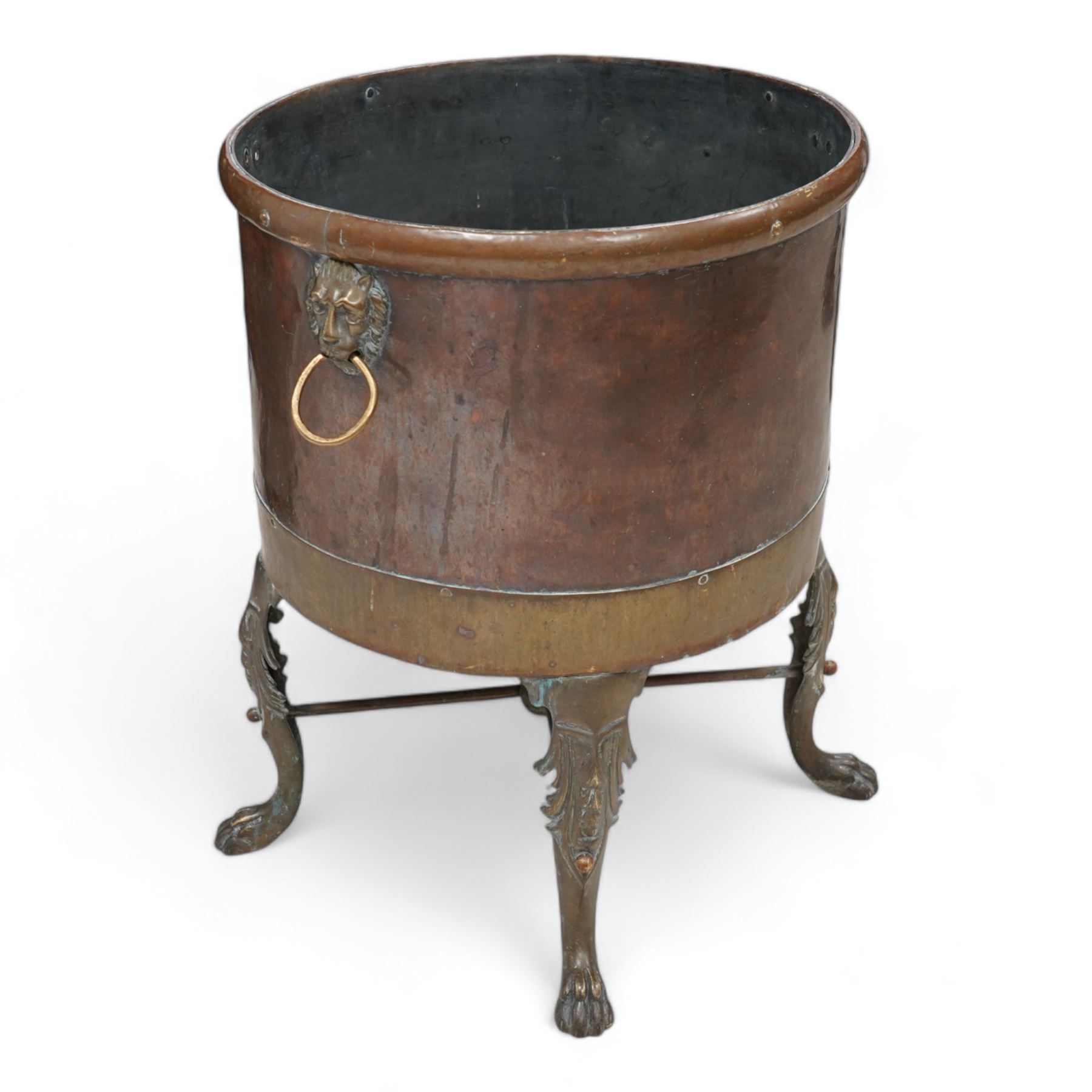 19th century copper and brass log basket, fitted with twin lion mask handles, raised on acanthus cast cabriole supports terminating to paw feet, united by X-stretcher