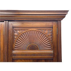 Late Victorian walnut triple wardrobe, projecting moulded cornice over central bevelled mirror door and flanking panelled doors, the top panels carved with fluted fans and stylised leaf motifs, the interior fitted with three linen slides, two drawers and hanging space, two long drawers to base, reed moulded uprights and vertical fluted horizontal rails 