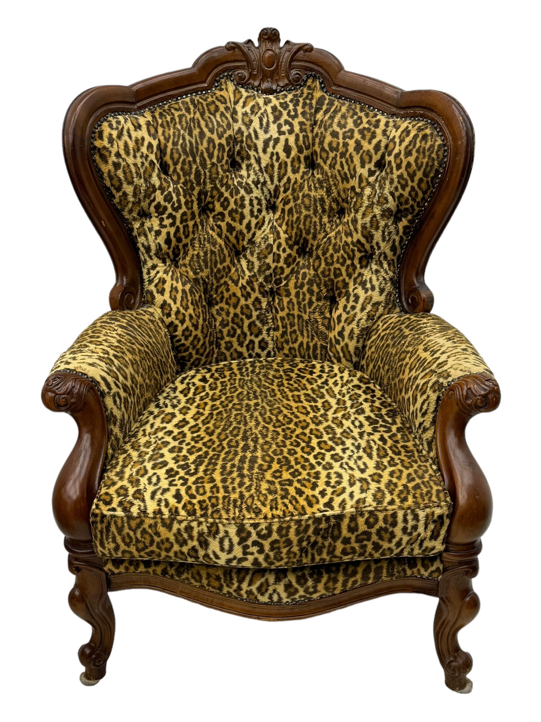 Pair of Victorian design stained beech armchairs, upholstered in leopard print fabric, with carved top rail over button-tufted backrest, scroll arms, serpentine front rail, raised on cariole supports