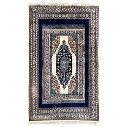 Indo-Persian indigo ground rug, the field depicting a rug with floral medallion and spandr...