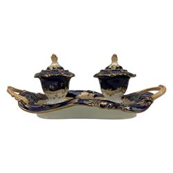 19th century porcelain inkstand, the oblong twin handled base centrally painted with a floral bouquet, flanked by two footed inkwells and covers, with rococo-inspired acanthus moulded borders and handles, pattern no. 2/3339, L26.5cm 