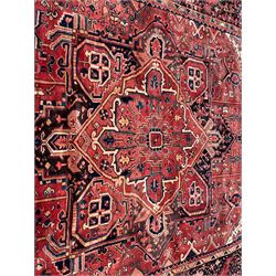 Persian Heriz red ground carpet, large central eight point medallion with projecting palmettes surrounded by small geometric motifs, decorated profusely with hooks, rosettes and animals, the busy border decorated with stylised foliate motifs within guard stripes 