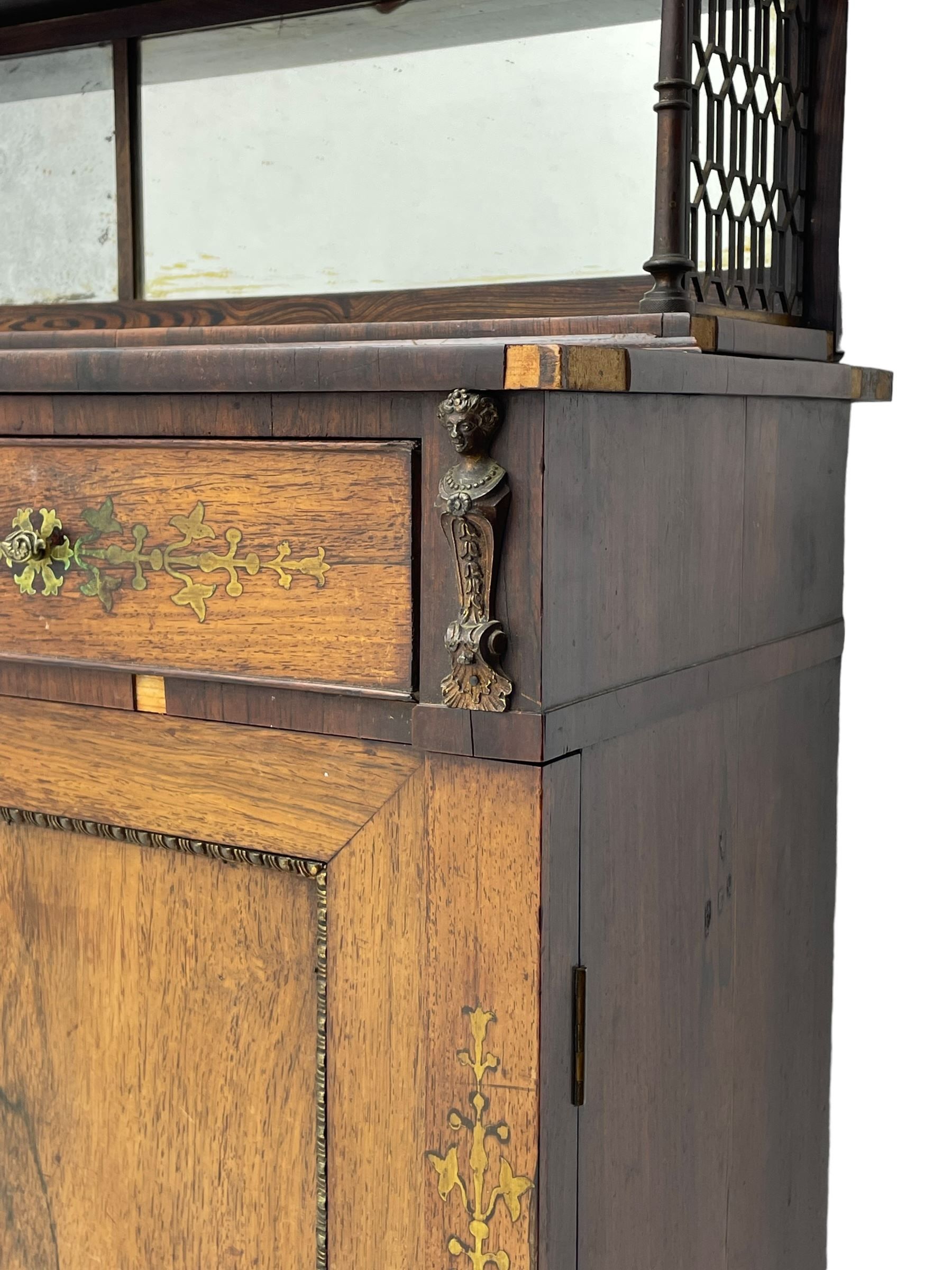 Attributed to John McLean & Son (London: 1770-1825) - Regency rosewood chiffonier, the raised two tier mirrored back on turned brass supports with brass trestle sides, rectangular top with brass stringing over two drawers and central cast brass satyr mask, cock-beaded drawer fronts inlaid with extending stylised foliate brass work, double cupboard below enclosed by panelled doors with cast egg and dart edging, matched brass inlays to the uprights, fitted with internal shelf, on turned compressed bun feet 