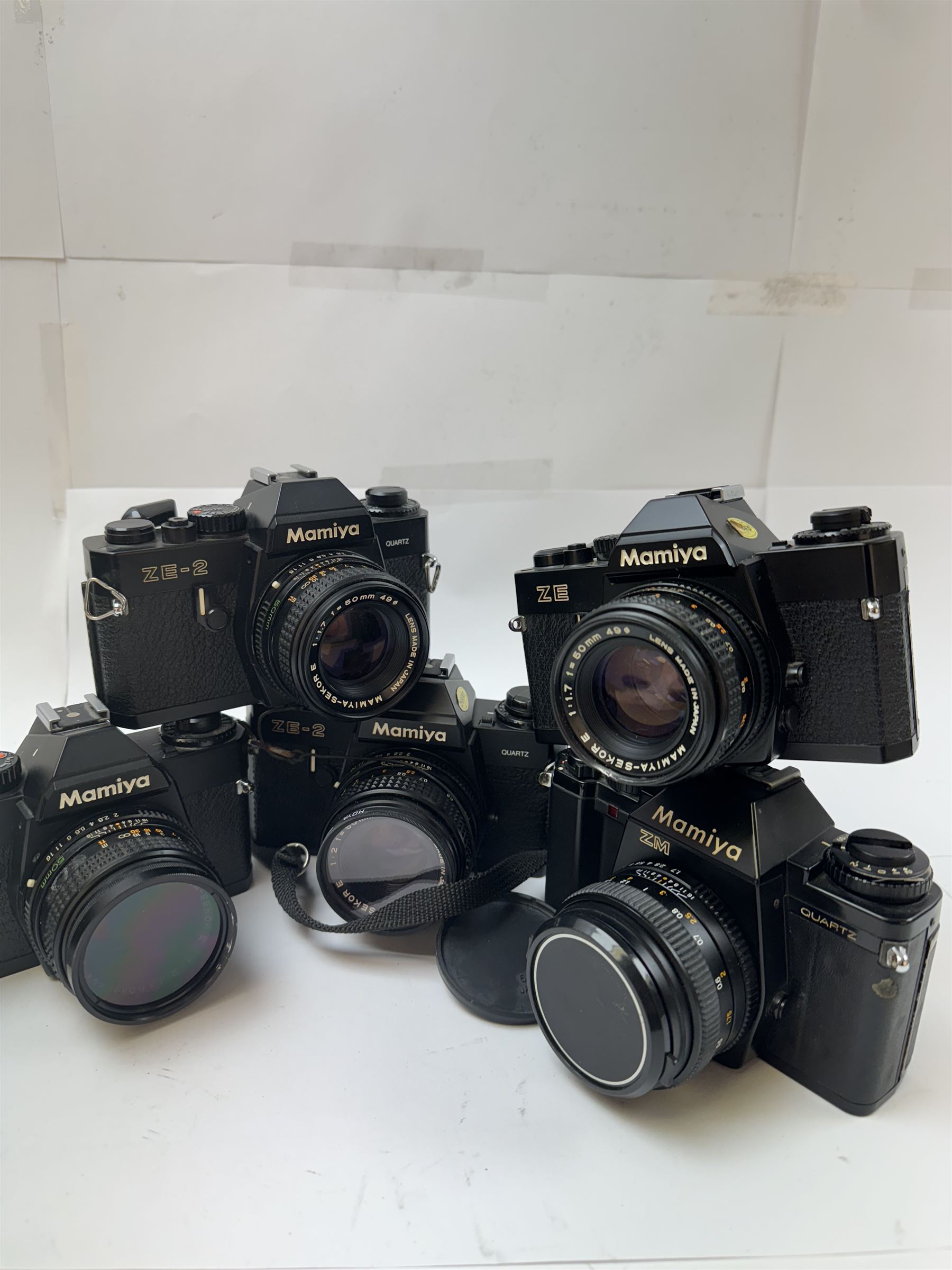 Five Mamiya SLR camera bodies, to include two ZE examples, serial nos. N171962 & N101512, one with a Mamiya-Sekor E 1:1.7 f-50mm lens serial no. 73984, the other with a Mamiya-Sekor E 1:2 f=50mm lens serial no. 48130, two ZE-2 camera bodies serial nos. N10753 & N328146, one with a Mamiya-Sekor E 1:1.7 f-50mm lens serial no. 93361 the other with a Mamiya-Sekor E 1:2 f=50mm lens serial no. 40170 and a ZM camera body serial no. V206108, with a Mamiya-Sekor E 50mm 1:1.7 S lens