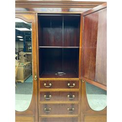 Edwardian inlaid mahogany combination wardrobe, projecting moulded cornice over figured frieze with satinwood banding, the central section fitted with cupboard over four long drawers, figured matched veneers and satinwood bands, flanked by two full height compartments enclosed by bevelled shield shaped mirror doors, satinwood fan inlaid spandrels, on moulded skirt base 