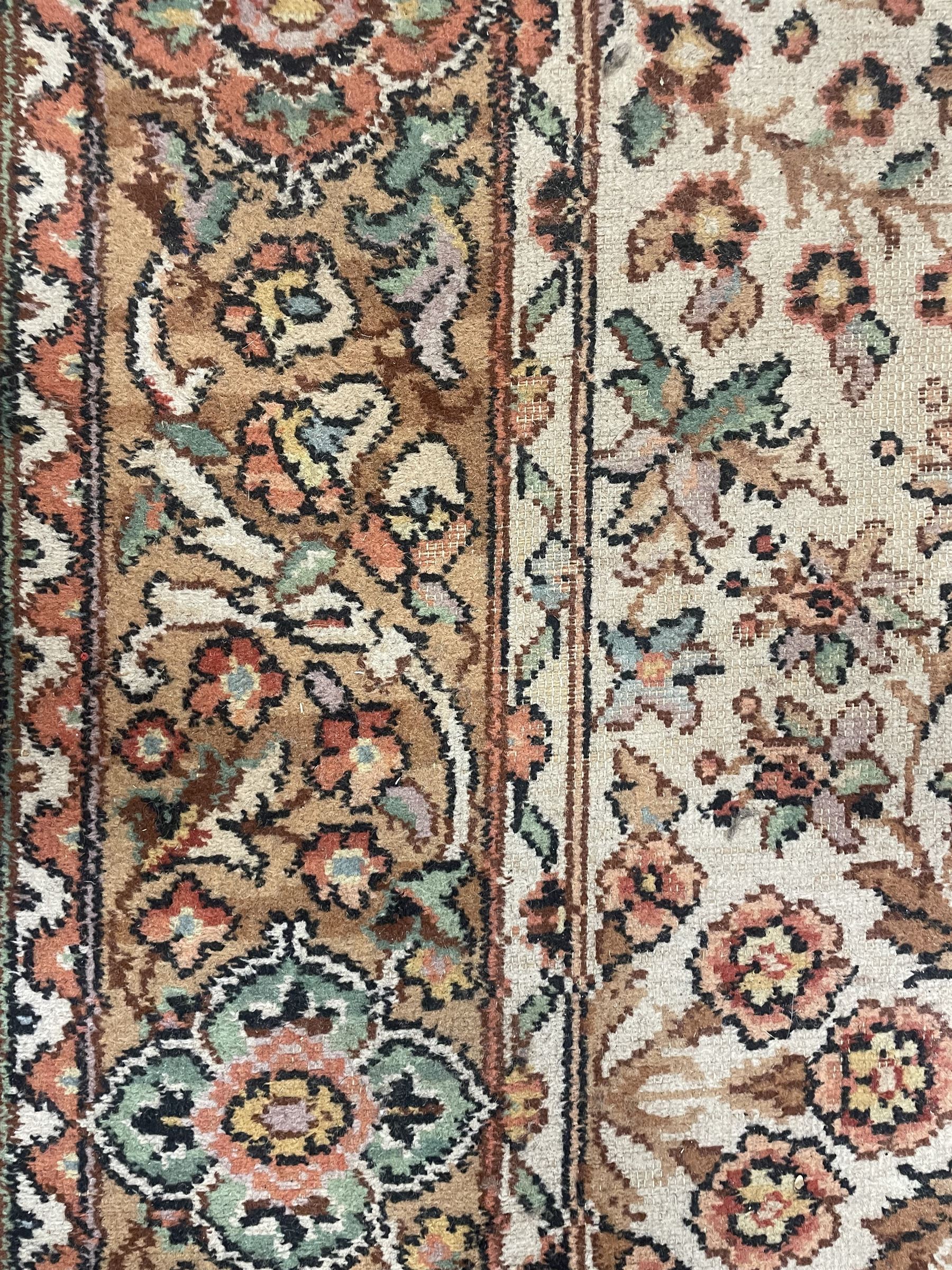 Large Persian design carpet, overall floral design, the field decorated with large rosette motifs surrounded by trailing foliate motifs, the border decorated with trailing branch and stylised plant motifs